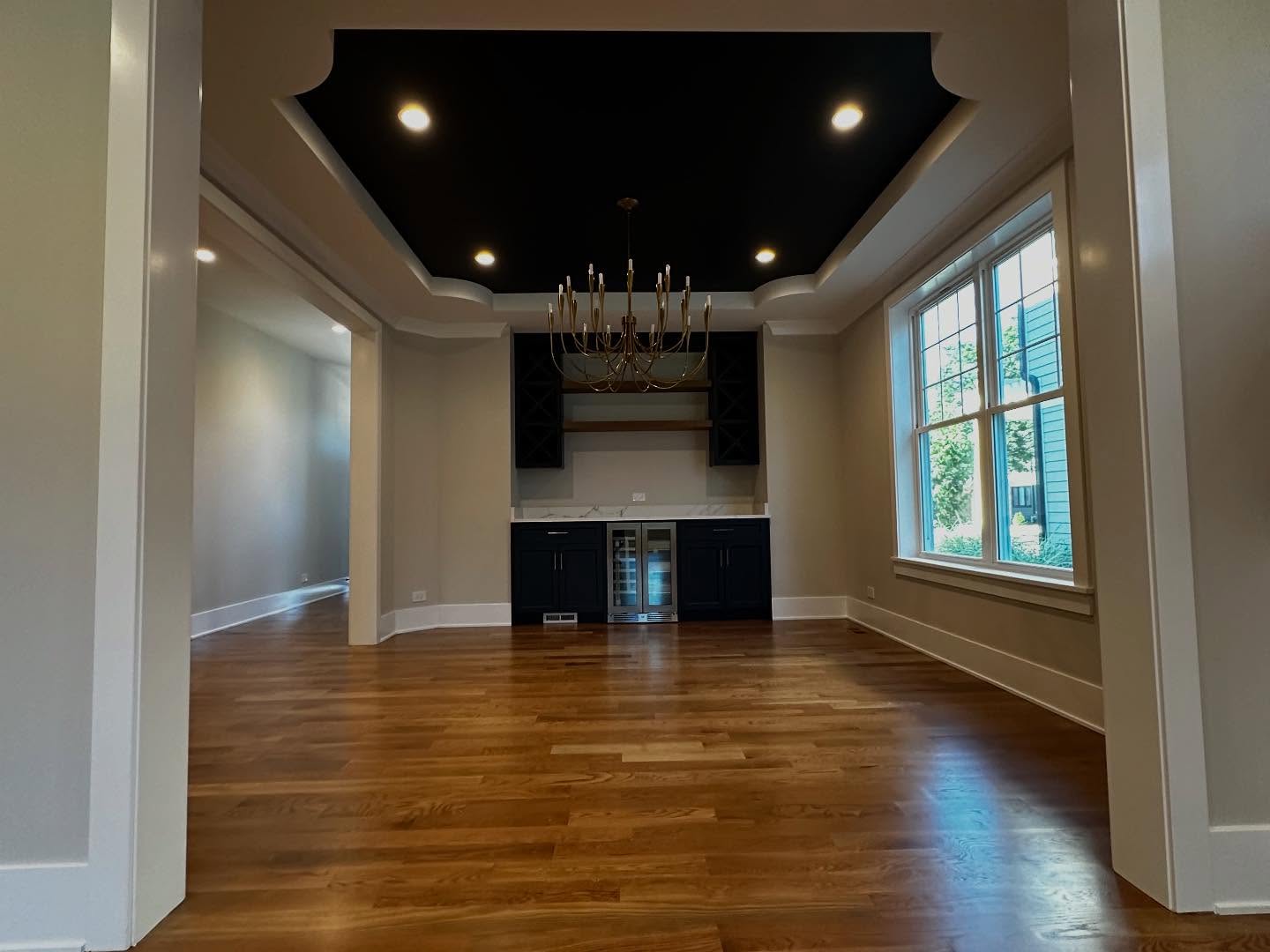 Wine bar with dark painted coffered ceiling and chandelier