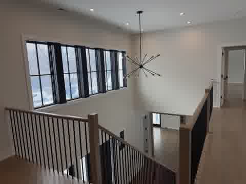 Double-height stairwell with pristine white walls, sputnik chandelier and hardwood floors, Northbrook