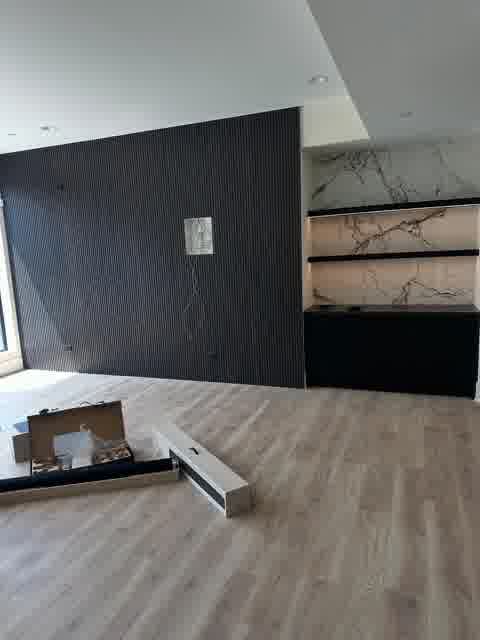 Living room with black fluted slat accent wall, marble-backed LED shelving unit and linear fireplace, Oak Brook