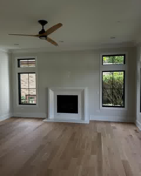 Living room with marble fireplace surround, ceiling fan and black-frame windows, Clarendon Hills